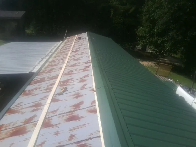 Old rusted panels beside newly installed green metal roofing — Wind Damage Roof Repair by Roofing Brothers in Graniteville