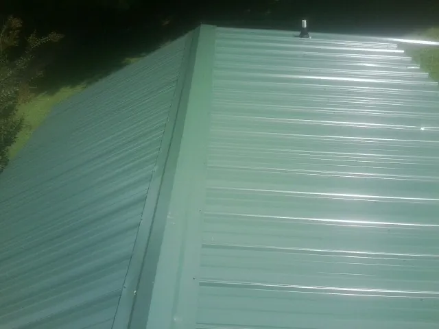 New green metal panels meeting at the ridge of a roof — Flat Roof Repair work by our crew in Graniteville