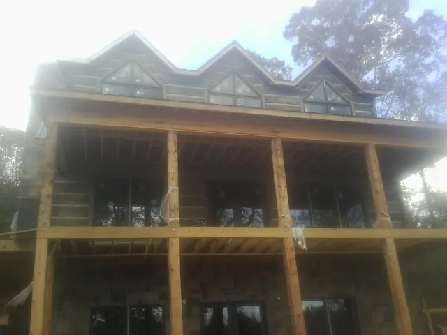 Dormers and porch framing on a large log home under construction — Roof Coating work by our crew in Graniteville