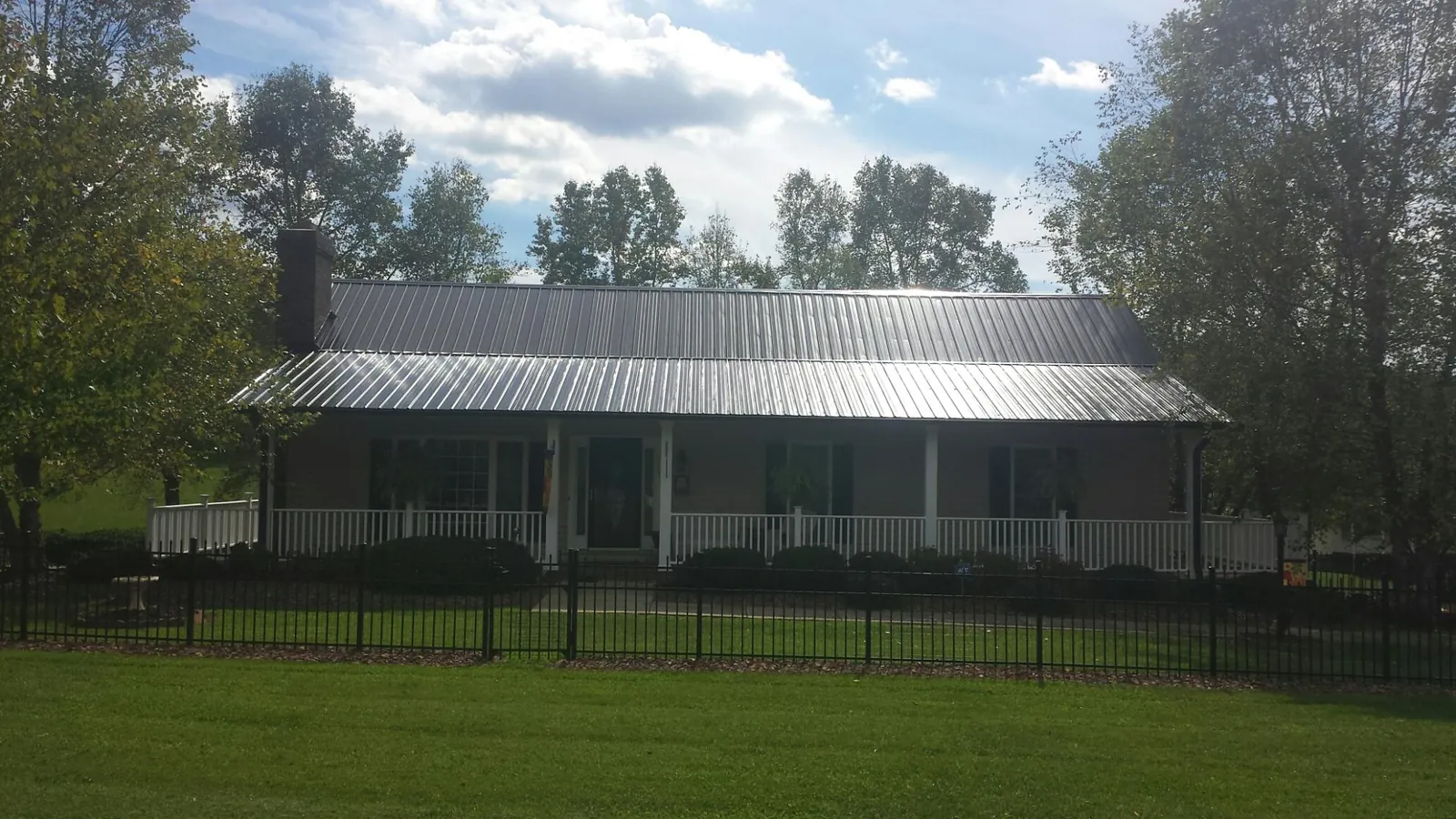 Gray metal roof on a brick ranch with a full width front porch — Gutter Guard Installation work by our crew in Graniteville