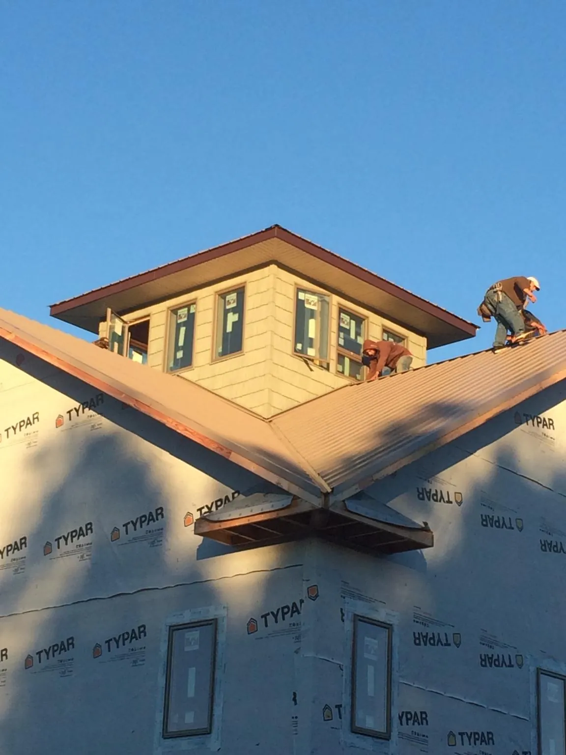 Roofers working around a rooftop cupola on a new metal roof at sunset — Roof Waterproofing in Graniteville by Roofing Brothers